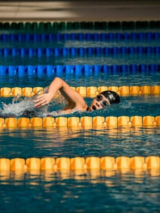 atleta nadando em piscinas com raias amarelas e azuis